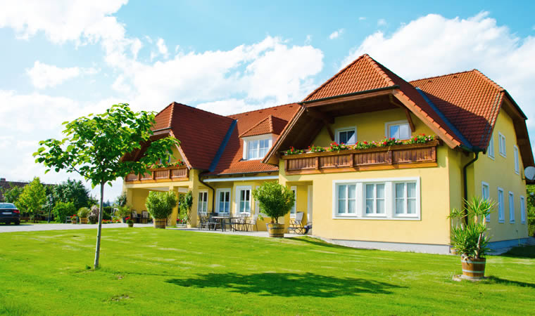 Haus von rechts vorne mit Vorgarten und Himmel